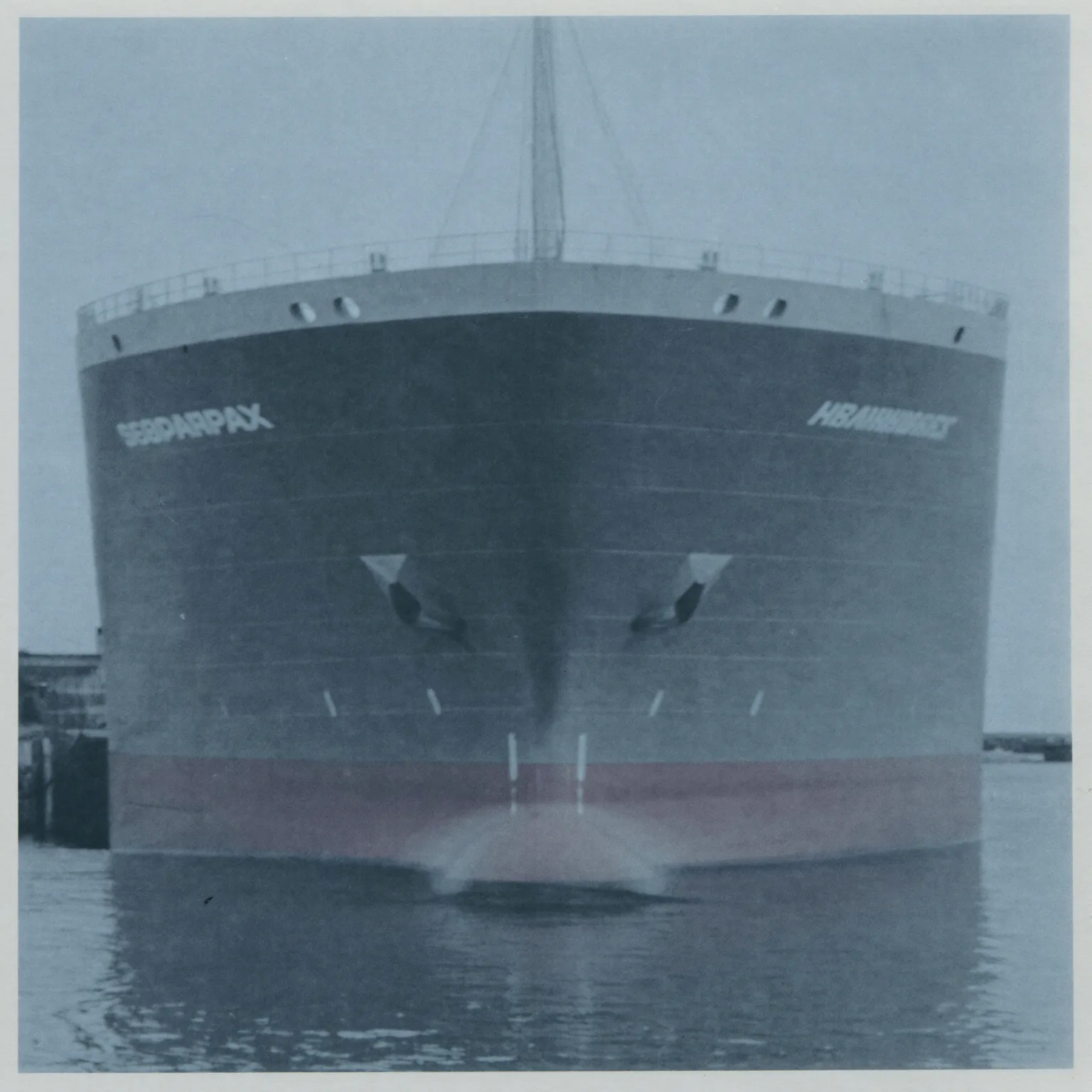 A supramax bulk carrier moored and idle in a grey harbour