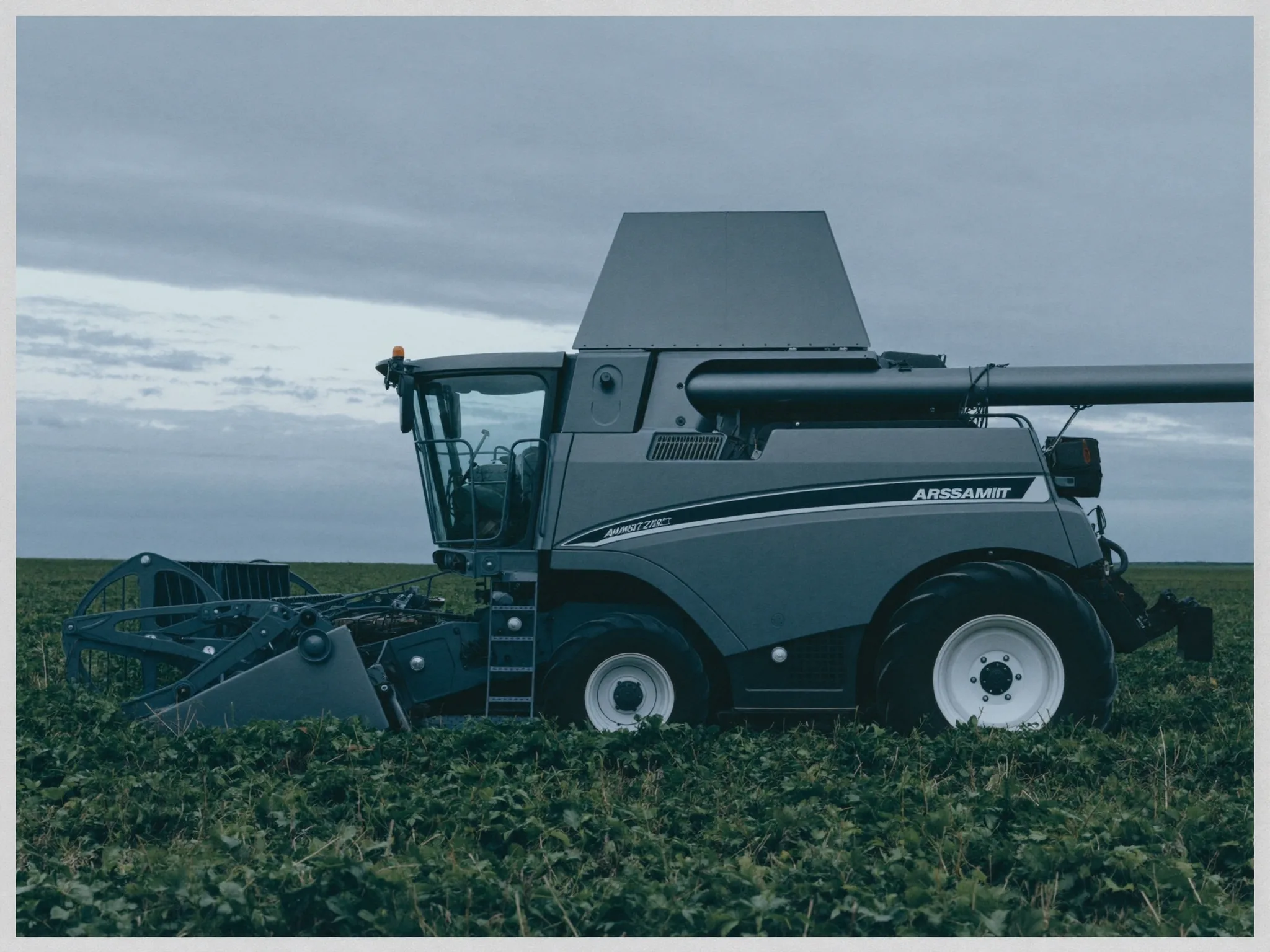 A combine harvester in a field at dusk