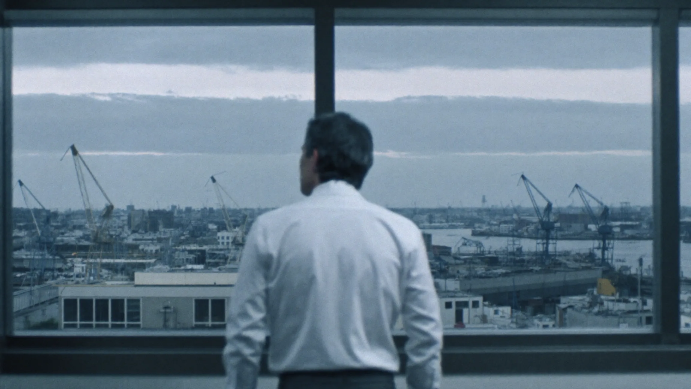 A founder in a quiet office with a coffee cup, cold steel light through the window
